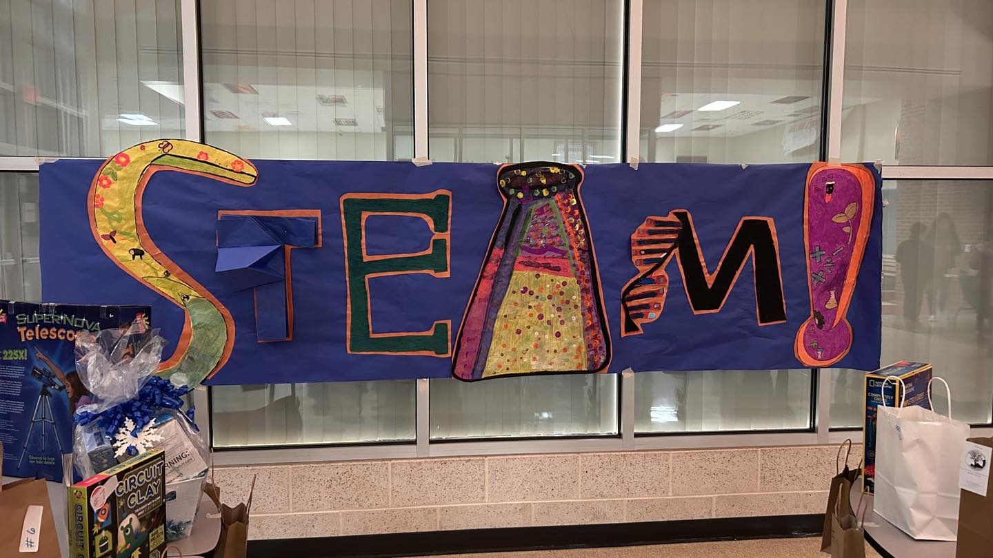 A painted mural hangs on the wall of the gym, reading STEAM