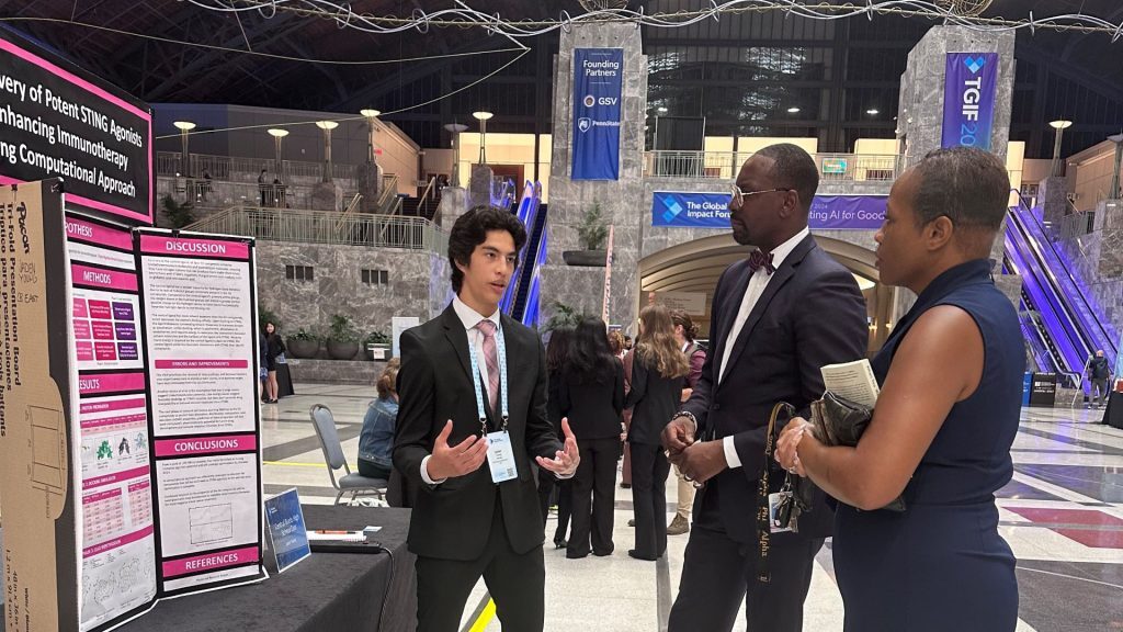 Jaden Young, Central Bucks High School, discusses his project Novel STING Agonists for Triple-Negative Breast Cancer with Immunotherapy with Secretary of Education Dr. Khalid Mumin, at center, and Cathy Hall, of the Pennsylvania Department of Education.