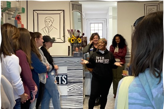 College students listen to the owner of a small bookstore speak about her collection of materials.