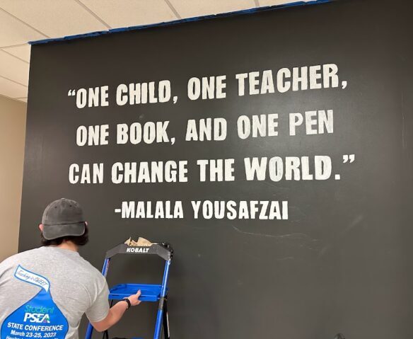 A quote by Malala Yousafzai written on a wall that says, "One child, one teacher, one book, and one pen can change the world."