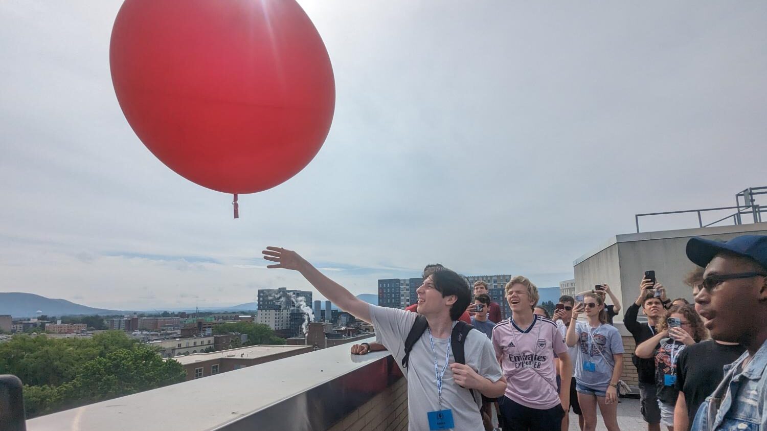 Students participating in Weather Camp at Penn State release a weather balloon from the roof of a parking deck.